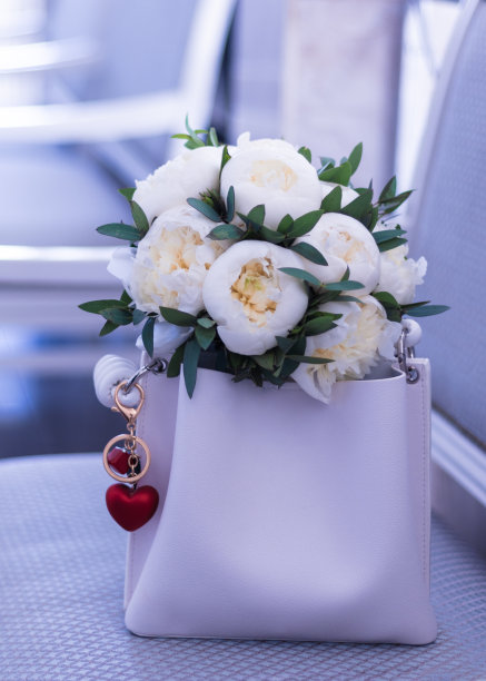 白色牡丹在米色包和钥匙链与心型图片下载