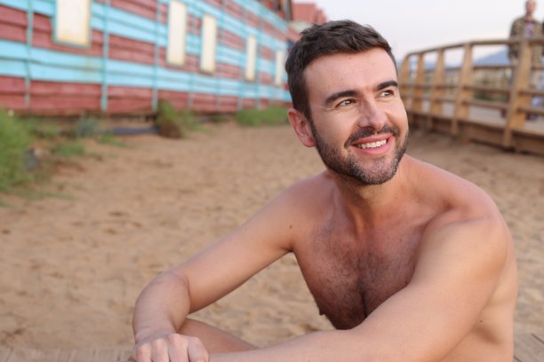 一个在海滩上微笑的赤膊帅哥图片下载
