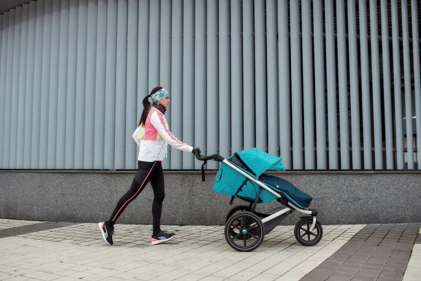 一个寒冷的秋天，女跑步者妈妈在城市里用婴儿车训练的全程照片图片下载