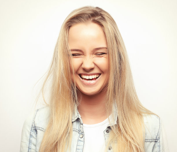 年轻的金发积极女性的肖像与愉快的表情，穿着休闲的衣服，在白色的背景。漂亮的女人室内图片下载