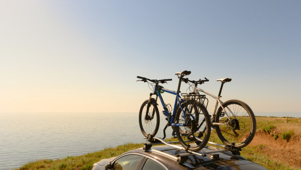 自行车在汽车的车顶上，在山的边缘，以大海和日落为背景。图片下载
