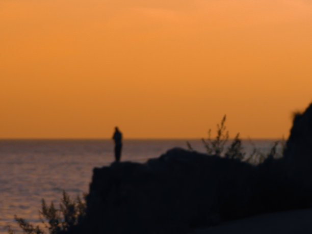 在日落和橙色的天空下，人们在钓鱼图片下载