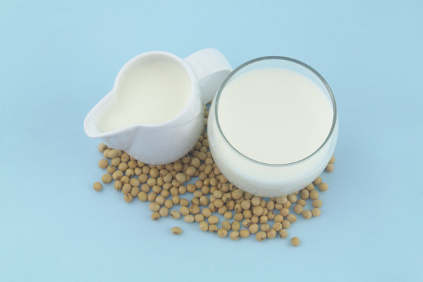 水罐和玻璃罐里的豆浆，蓝色背景上有大豆图片下载