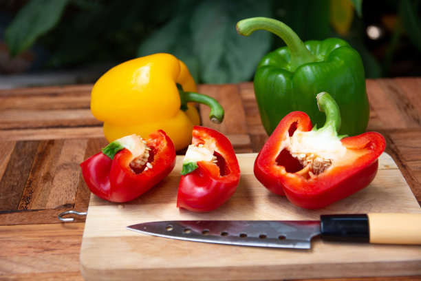 在木地板上切红、绿、黄三色的甜椒。图片下载