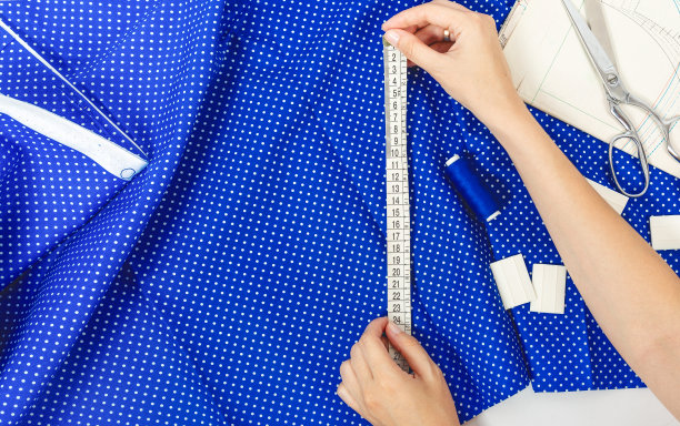 在设计工作室工作。一位女设计师用卷尺量布料。一个制造服装的专有概念。裁剪图片下载