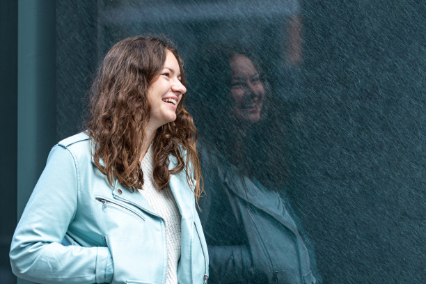 一个年轻性感的黑发女人的肖像与长头发抛光的深色大理石墙壁图片下载