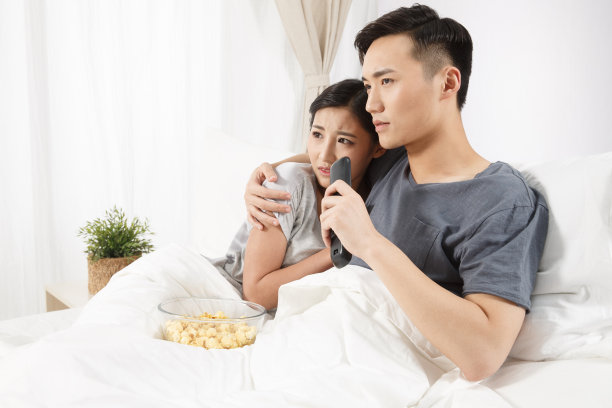 青年情侣坐着床上看电视图片下载