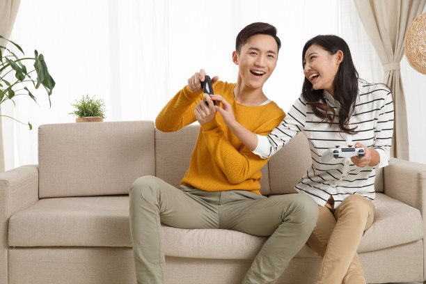 青年情侣坐着沙发上玩游戏图片下载