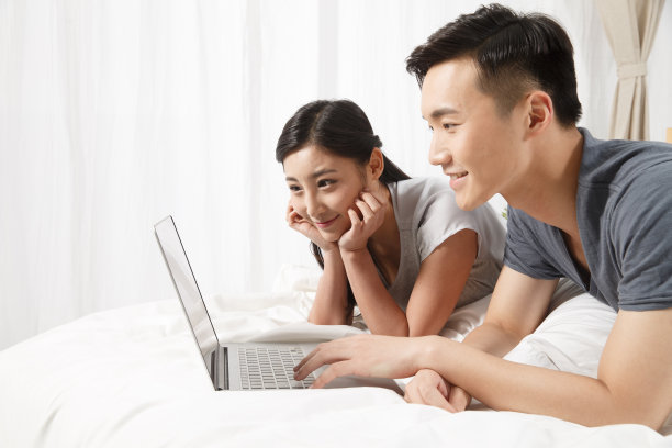 青年情侣趴在床上看电脑图片下载