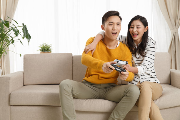 青年情侣坐着沙发上玩游戏图片下载