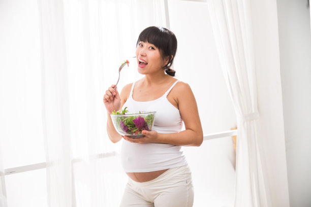 幸福的孕妇吃蔬菜沙拉图片下载