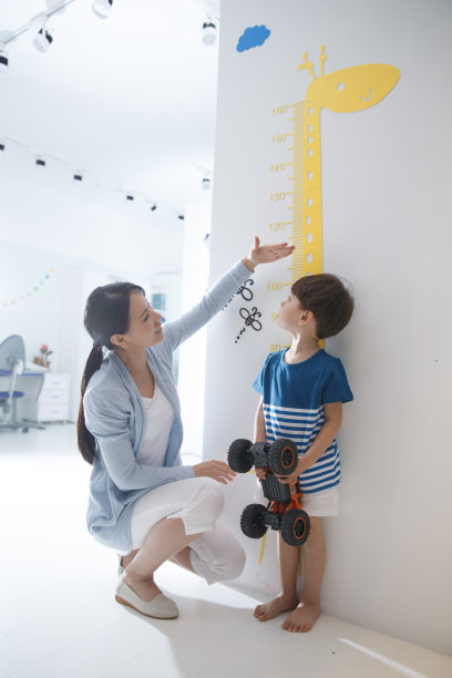 青年女人在为小男孩测量身高图片下载
