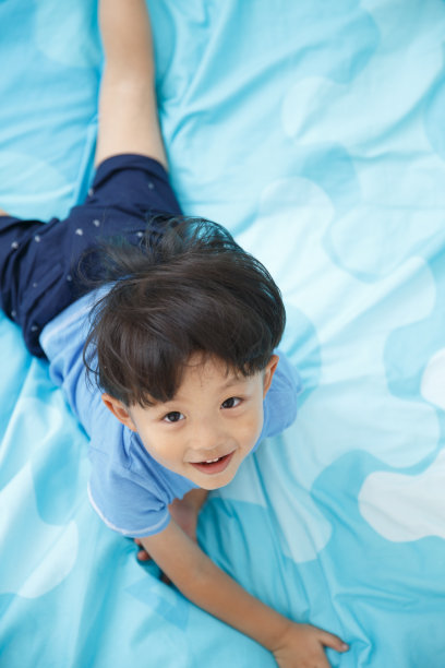 可爱的小男孩在床上玩耍图片下载