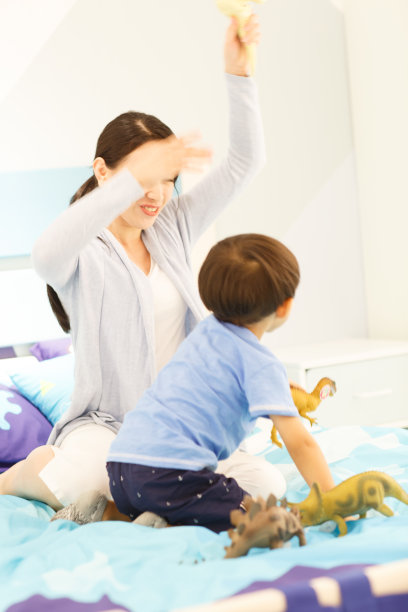 可爱的小男孩和妈妈在卧室玩耍图片下载