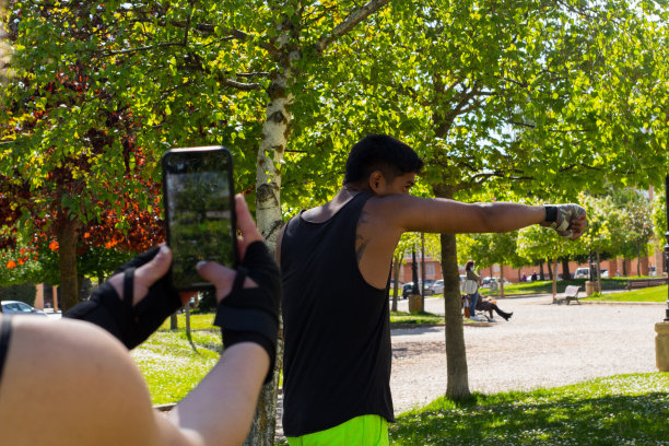 年轻的拳击手在户外训练，他的搭档用他的手机给他拍照图片下载