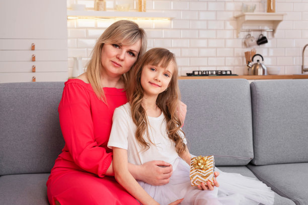 母亲节快乐。8-9岁的女儿和她的妈妈看着摄像机。妈妈和女孩微笑着拥抱着。家庭假期和团聚。图片下载