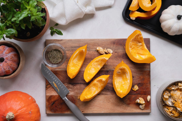 俯瞰砧板上新鲜的橙色南瓜片。制作白胡桃汤、馅饼或秋季食物的配料。图片下载