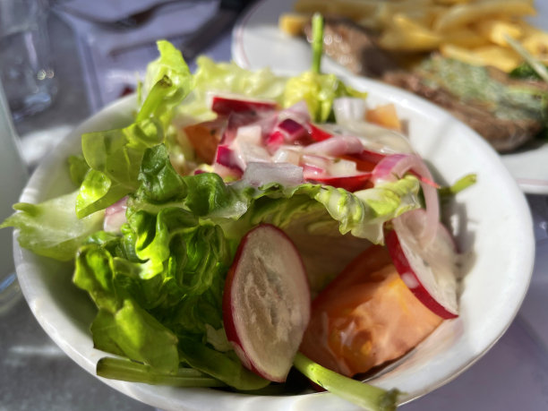 餐厅场景的特写图片，餐桌与一餐烤黑安格斯牛排与融化的大蒜黄油，炸薯条炸薯条和豆瓣菜在白色盘子旁边的碗沙拉，吃户外餐饮，高架的视野，聚焦前景图片下载