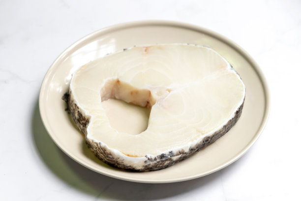 雪鱼装在盘子里，美味可口。雪鱼产于深海，厚片状，入口即化。孤立在白色大理石桌子背景上。图片下载