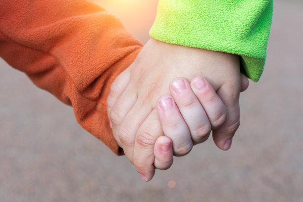 在模糊的背景上，孩子们手牵着手的特写镜头。我们的理念是:友谊从小开始，朋友一辈子，兄弟永远在一起。水平的照片图片下载