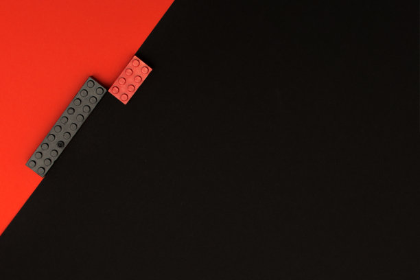 对比黑色和红色的背景，构造者的玩具积木对角地躺在上面，黑色和红色。创意-背景，文字，广告的位置。图片下载