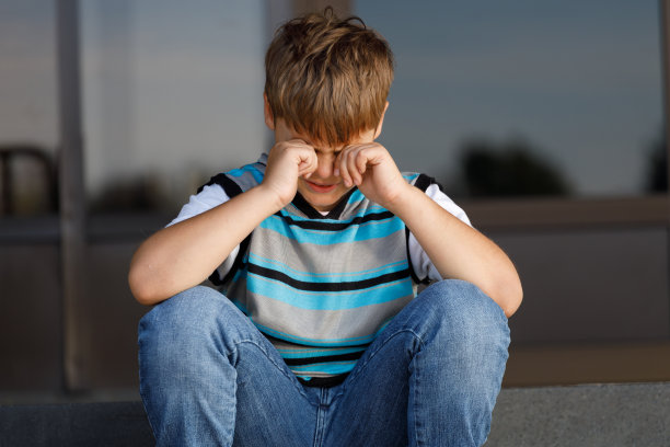 穿着条纹毛衣的小男孩坐在台阶上哭泣图片下载