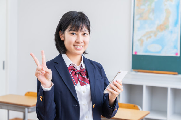 在教室里学习的亚洲女学生，智能手机，校服图片下载