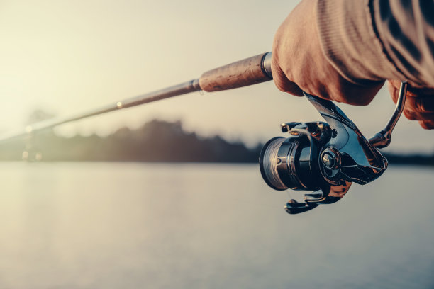 渔夫手里拿着一根旋转的鱼竿。钓鱼的背景图片下载