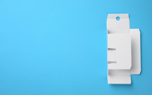 保护纸从一个有香水的盒子下，模板从白色瓦楞纸板，蓝色背景图片下载