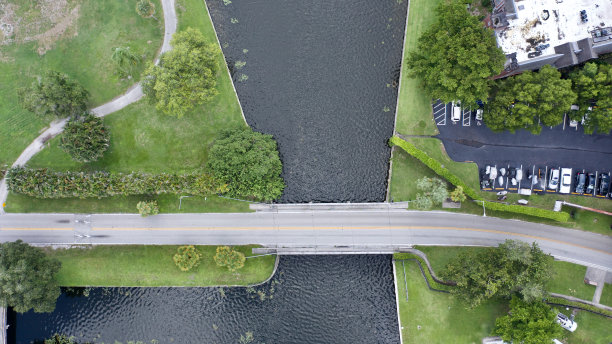 在佛罗里达劳德代尔堡一个阳光明媚的日子里，从上往下拍摄的照片正对着一条穿过一片水域的空马路。图片下载
