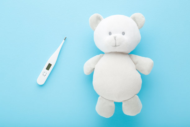 白色的泰迪熊和数字温度计在浅蓝色的桌子背景。柔和的颜色。特写镜头。儿童体温测量。医疗保健的概念。自顶向下的观点。图片下载