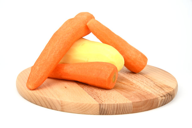 在木制砧板上削胡萝卜和土豆皮。图片下载