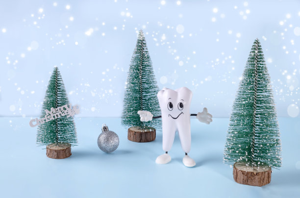 一个牙齿的卡通模型，有一个球的圣诞树和蓝色背景上的题词“快乐的圣诞节”图片下载