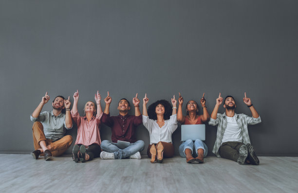 摄影棚拍摄了一群不同的人指着灰色的背景图片下载