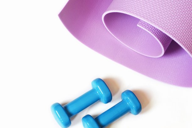 俯视图健身器材在白色背景。卷着紫色的垫子和蓝色的哑铃。健身，运动理念，健康的生活方式图片下载