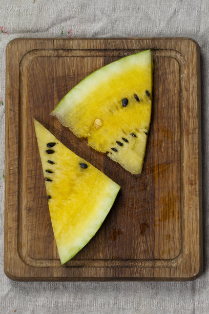 木制背景上的黄色西瓜片。图片下载