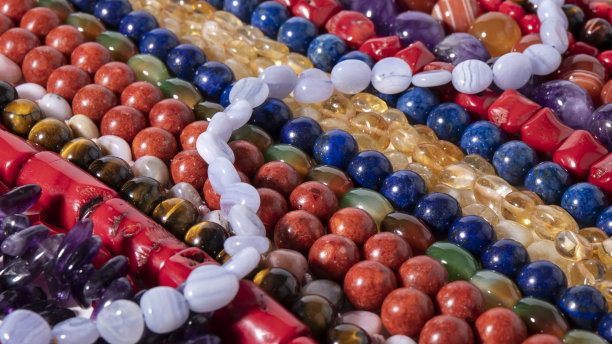 由天然石头制成的各种彩色珠子。美丽的珠宝。石头的背景。图片下载