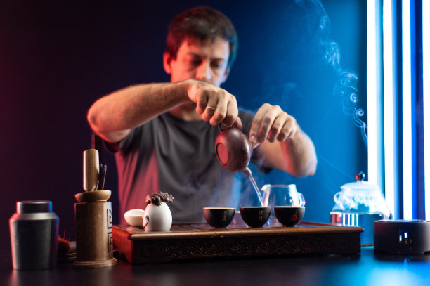一名男子在茶几上泡茶，桌上摆放着中国传统的器具图片下载