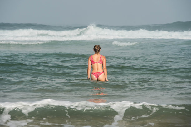 美丽的年轻女子在大西洋的波浪中嬉戏图片下载