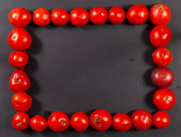 红色西红柿在黑色背景上的矩形框架。水平的。图片下载