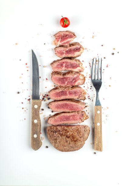 煎熟的牛排切成块，配上香料和餐具，白色背景。前视图。图片下载