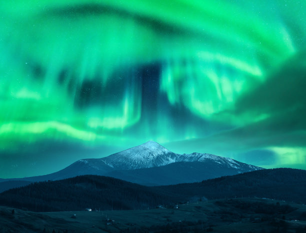 欧洲冰雪覆盖的山峰上的北极光。冬天的北极光。夜晚的风景与绿色的极地灯和雪山小山。星光灿烂的天空。大自然。空间图片下载