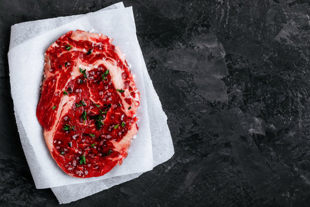 生小牛肉放在纸上，盐和百里香放在深色的石头混凝土背景上图片下载