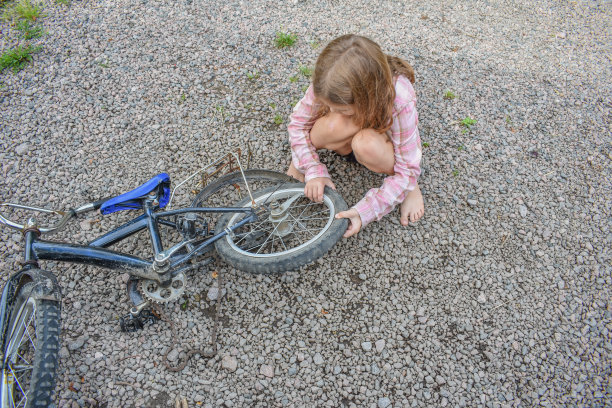 一个小女孩损坏了一个自行车轮子，正在修理照片没有处理图片下载