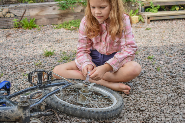 一个小女孩损坏了一个自行车轮子，正在修理照片没有处理图片下载