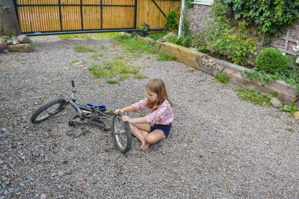 一个小女孩损坏了一个自行车轮子，正在修理照片没有处理图片下载