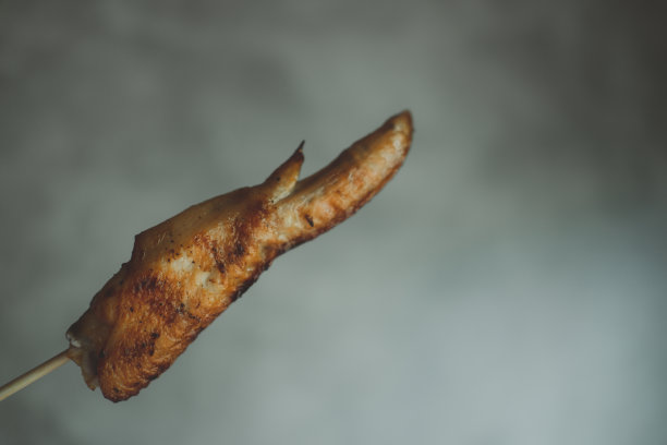 手拿竹签烤鸡翅。泰国风格的食物图片下载
