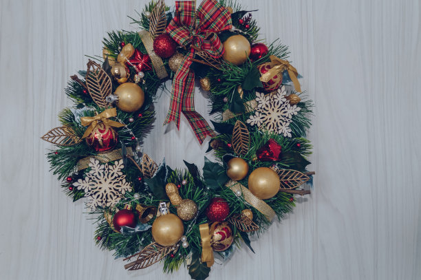 近距离观察手工制作的圣诞花环，装饰有圣诞球，坚果雪花和格子蝴蝶结图片下载