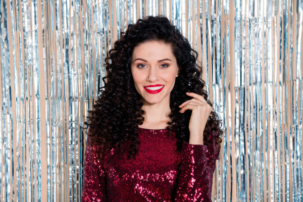 照片的年轻美丽微笑积极的女人与波浪头发享受自己的派对孤立在闪闪发光的背景图片下载