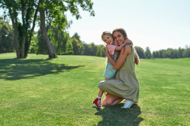 快乐的年轻母亲在夏天的公园里拥抱她的女儿图片下载